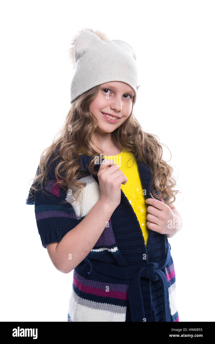 Niedliche kleine lächelnde Mädchen mit lockige Frisur tragen bunte Pullover, Hemd, Hose und Hut isoliert auf weißem Hintergrund. Winterkleidung Stockfoto