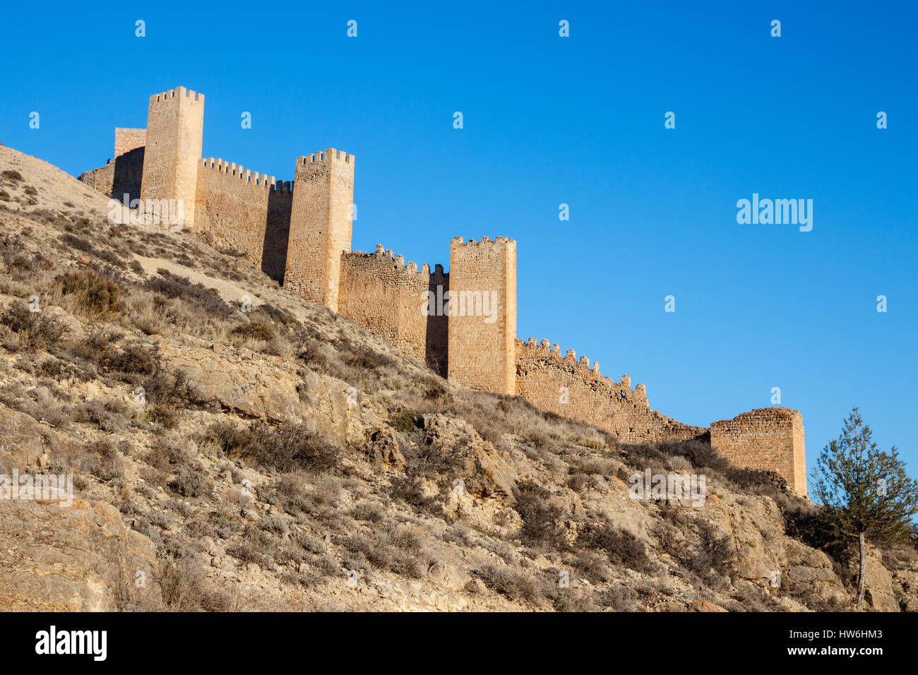 Hügel mit alten Stadtmauer mit Türmen unter blauem Himmel kreuzte. ALBARRACIN, Teruel, Spanien. Stockfoto