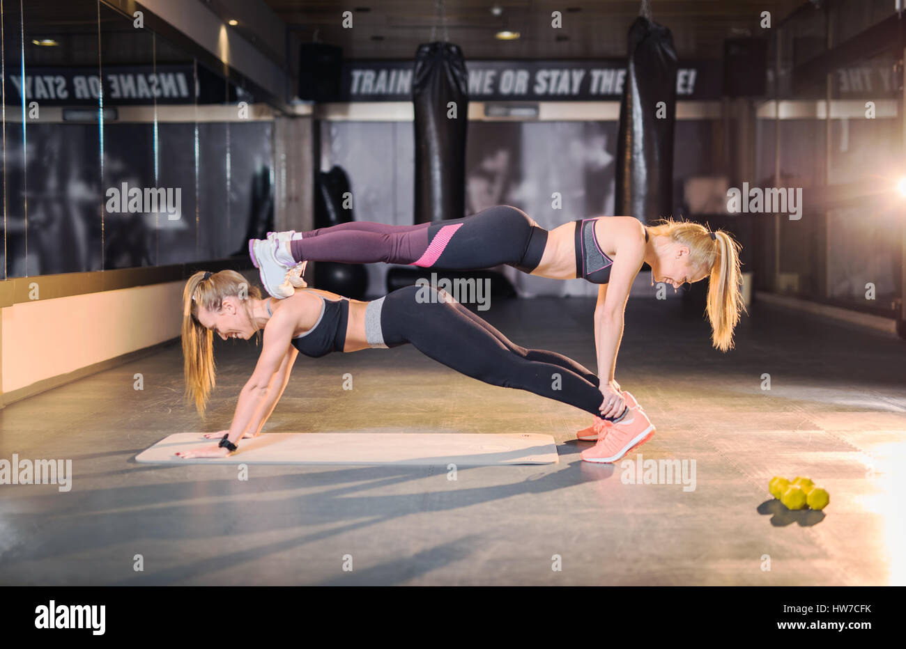 Zwei schöne sportliche Frauen tun Push ups auf einander Stockfotografie