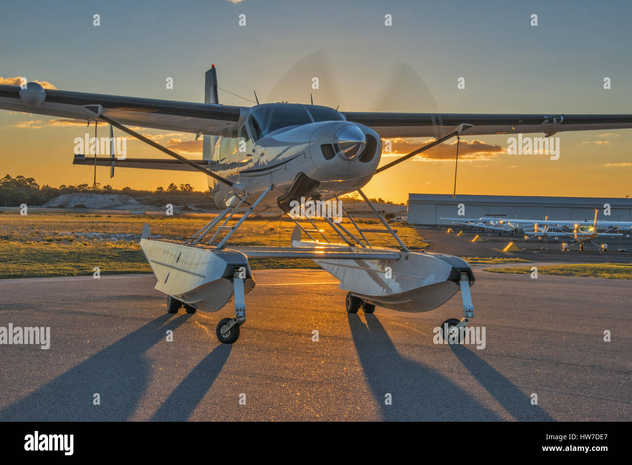 Schweben Sie ausgestatteten Cessna 208 Caravan Flugzeuge mit Motorlauf, Hintergrundbeleuchtung von der untergehenden Sonne Stockfoto