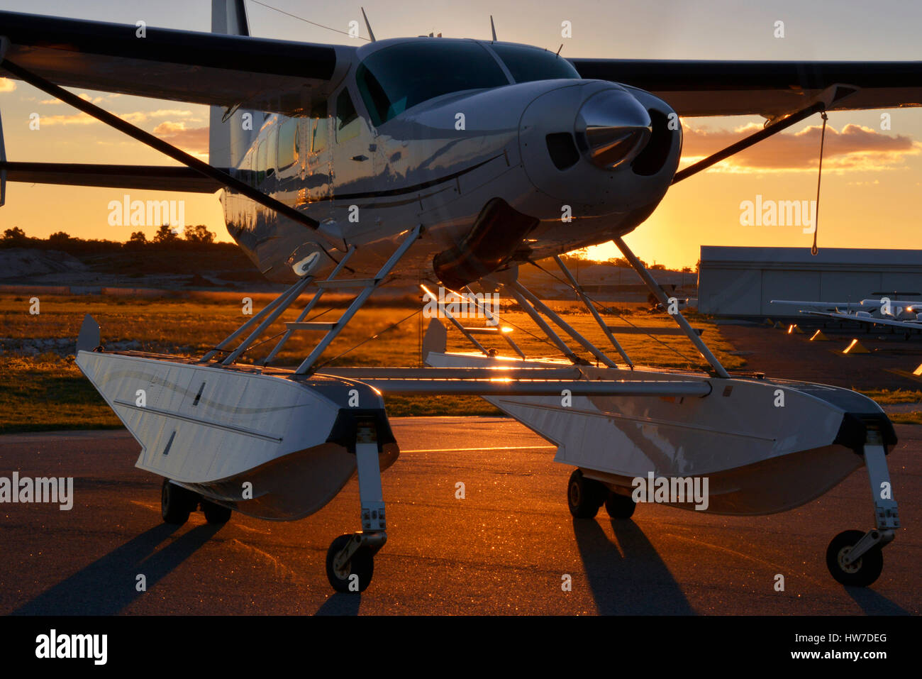 Schweben Sie ausgestatteten Cessna 208 Caravan Flugzeuge mit Motorlauf, Hintergrundbeleuchtung von der untergehenden Sonne Stockfoto