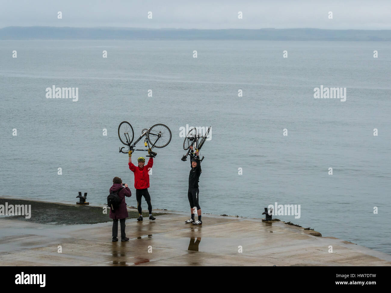 Radfahrer feiern Ende der Fahrradtour, die ihr Foto auf Pier, North Berwick, East Lothian, Schottland, UK, Leihfahrräder angehoben über den Köpfen Stockfoto