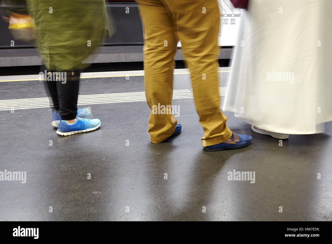 Beine und Schuhe von drei Personen warten auf einen Zug an der u-Bahn-Station. Stockfoto