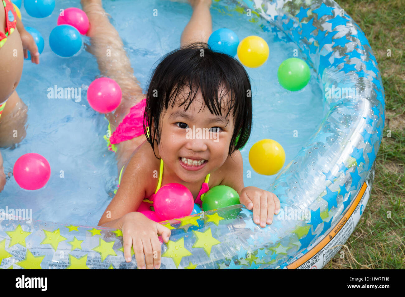 Asiatische chinesische Mädchen spielen in einen aufblasbaren Kautschuk-Swimmingpool im freien Stockfoto