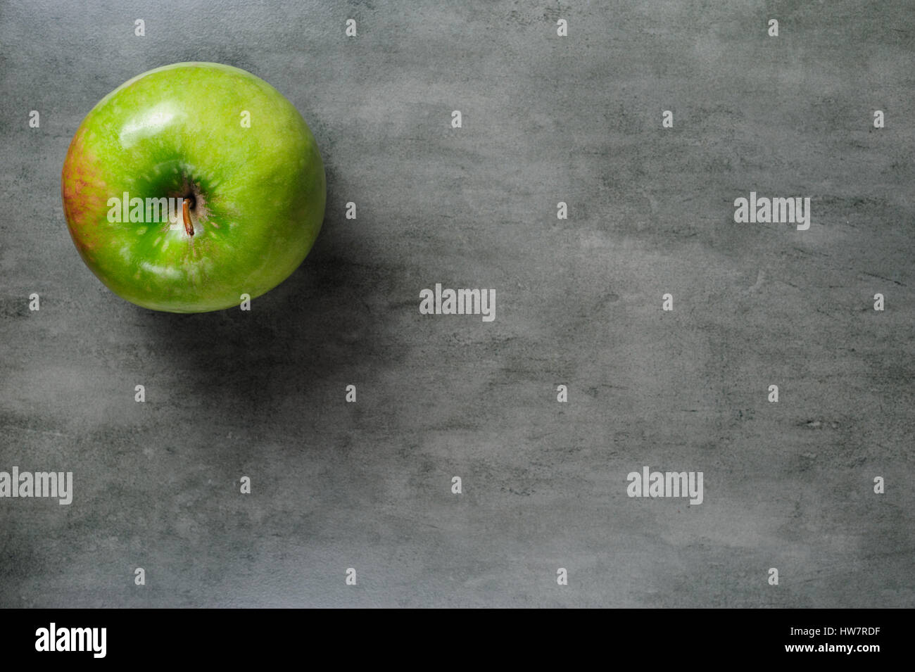 ein grüner Apfel auf dunklen Stein Hintergrund, Ansicht von oben. Stockfoto