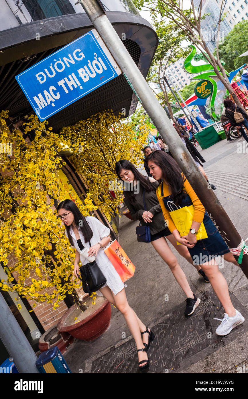 Drei junge Frauen, die zu Fuß rund um eine Straßenecke, Ho-Chi-Minh-Stadt, Vietnam Stockfoto