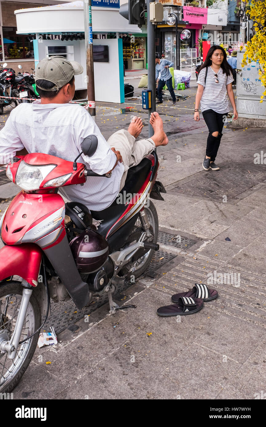 Motorradfahrer mit den Füßen oben auf Straßenecke, Ho-Chi-Minh-Stadt, Vietnam Stockfoto