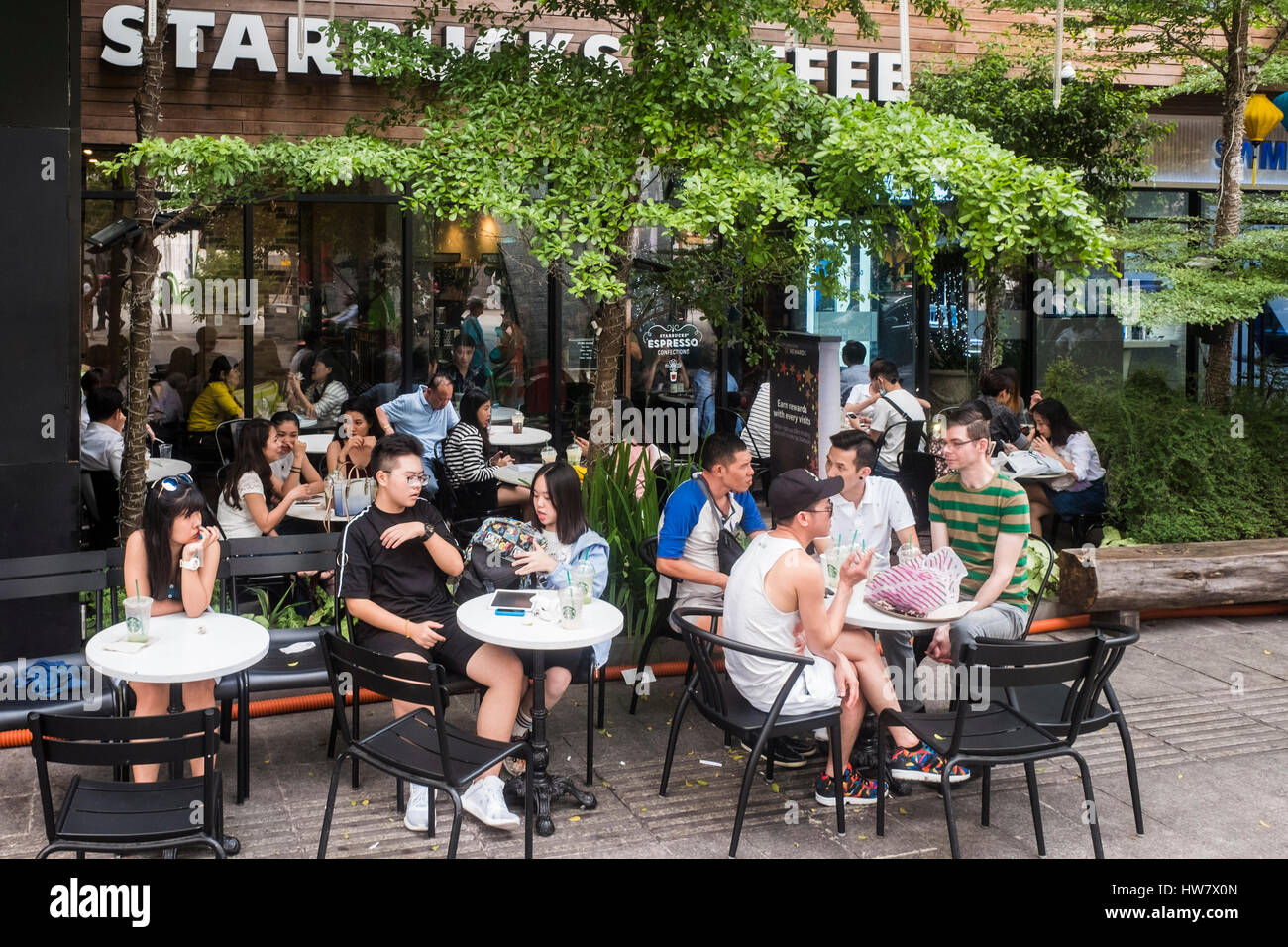 Junge Leute sitzen draußen Kaffee von Starbucks, Ho-Chi-Minh-Stadt, Vietnam Stockfoto