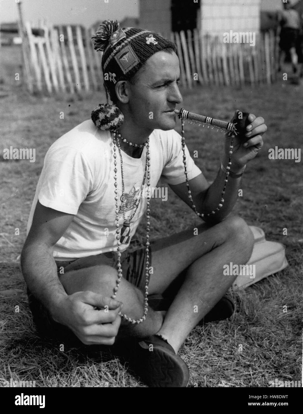 8. August 1957 - Scouts auf World Jubilee Jamboree. Besucher aus Südafrika. Pfadfinder aus allen Teilen der Welt nehmen Teil am Jamboree, heute im Sutton Park, Warwickshire öffnet. Das Foto zeigt Scout Master Rex. E. Abbott von East London, Südafrika, gut geschmückt mit Perlenstickerei Native Pfeife im Lager heute Rauchen. (Kredit-Bild: © Keystone Presseagentur/Keystone USA über ZUMAPRESS.com) Stockfoto