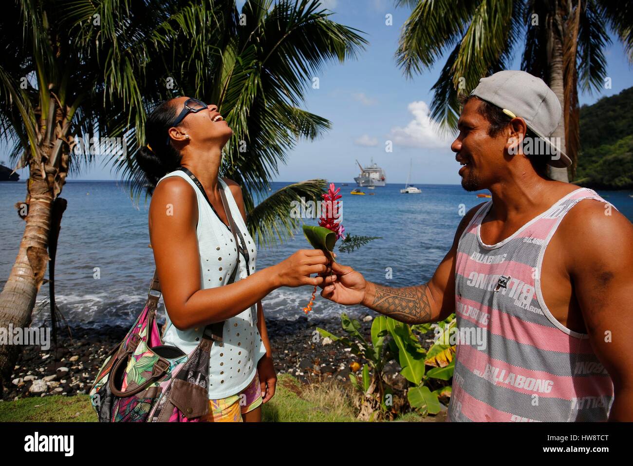 Frankreich, Französisch-Polynesien, Aranui 5 Frachter und Passagier Kreuzfahrtschiff zum Archipel der Marquesas-Inseln, Tahoata Insel, Dorf Vaitahu bietet eine Blume mit einer lachenden Frau Mann Stockfoto