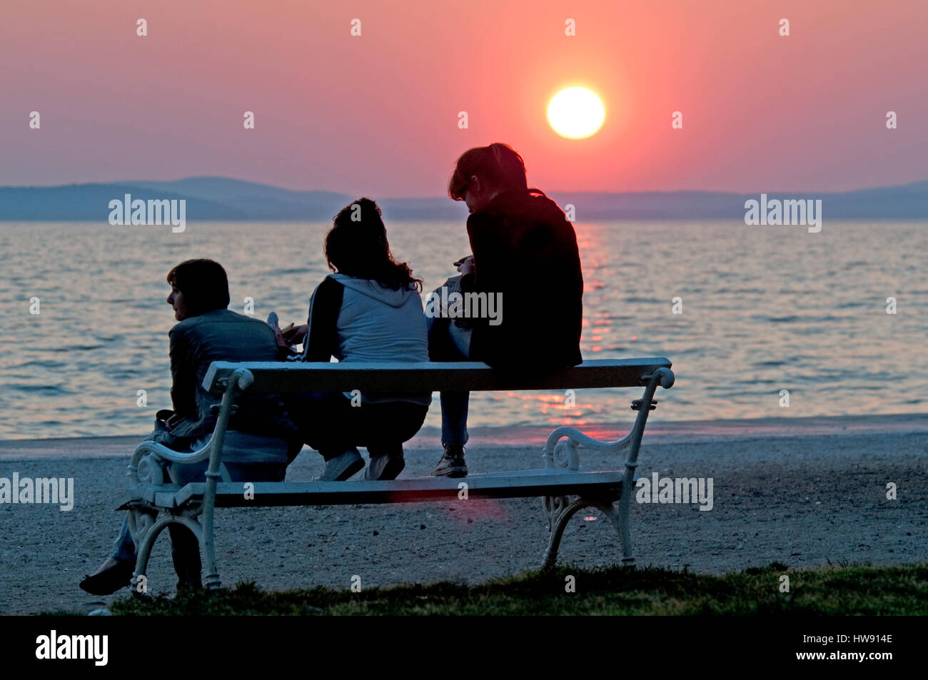 Zadar, Kroatien, 18.04.11: Leute sitzen draußen im schönen Sonnenuntergang am Horizont über dem Meer Stockfoto