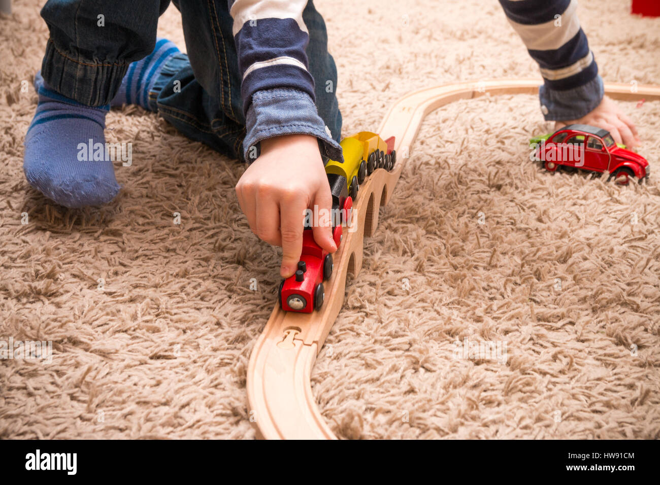 Detail eines kleinen Jungen mit Holzeisenbahn drinnen spielen. Stockfoto