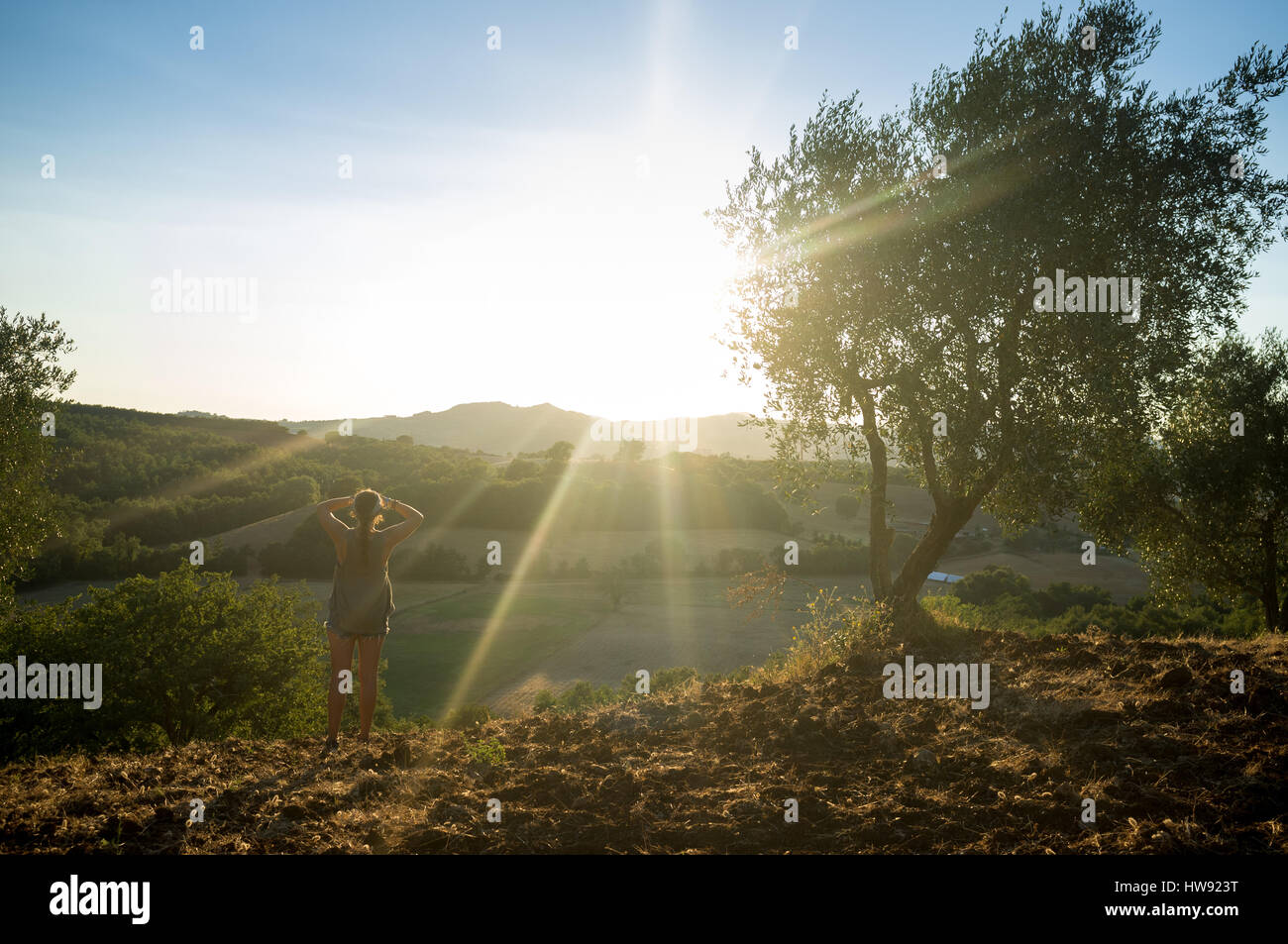 Frau hält auf einer Wanderung an, um den Sonnenuntergang zu genießen Stockfoto Frau hält auf einer Wanderung an, um den Sonnenuntergang zu genießen Stockfoto