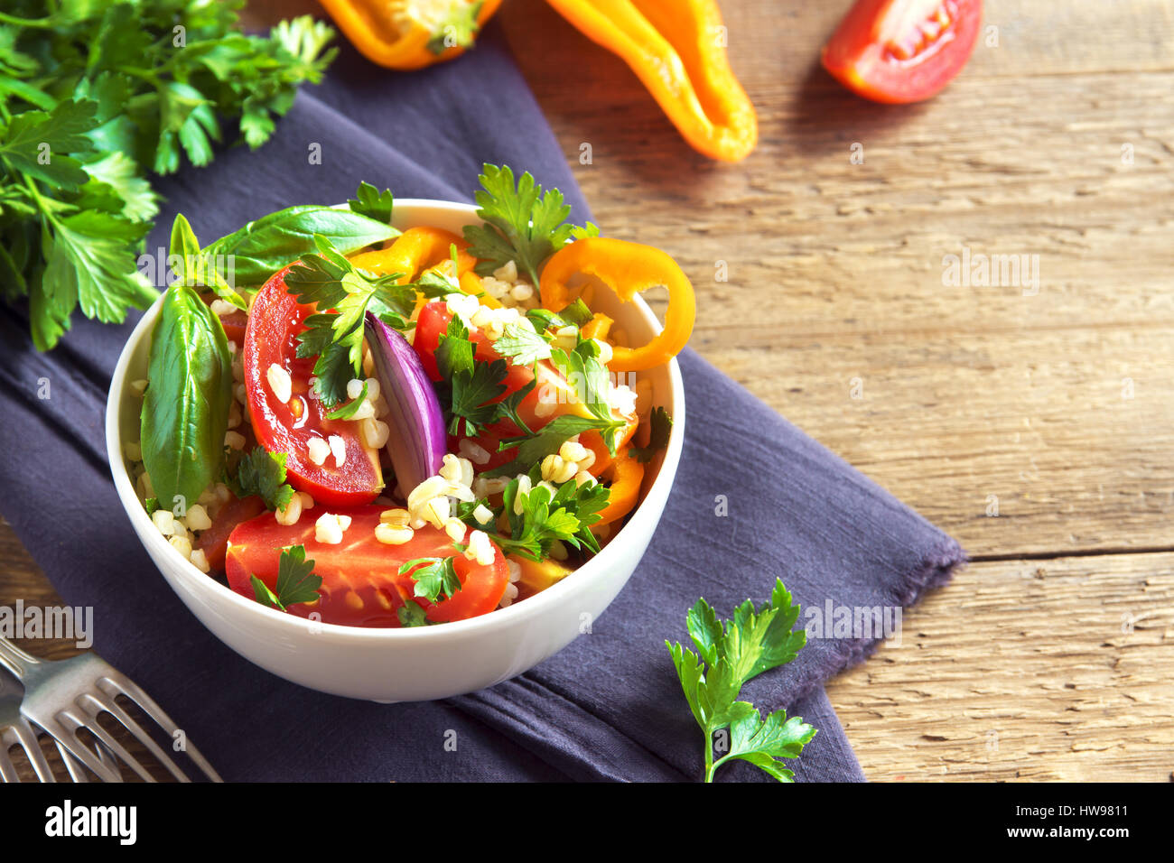 Frische Bio-Tomaten und Bulgur Couscoussalat Taboulé mit Gemüse und grünen - gesunde vegetarische vegane Ernährung traditionellen Salat auf rustikal aus Holz Stockfoto