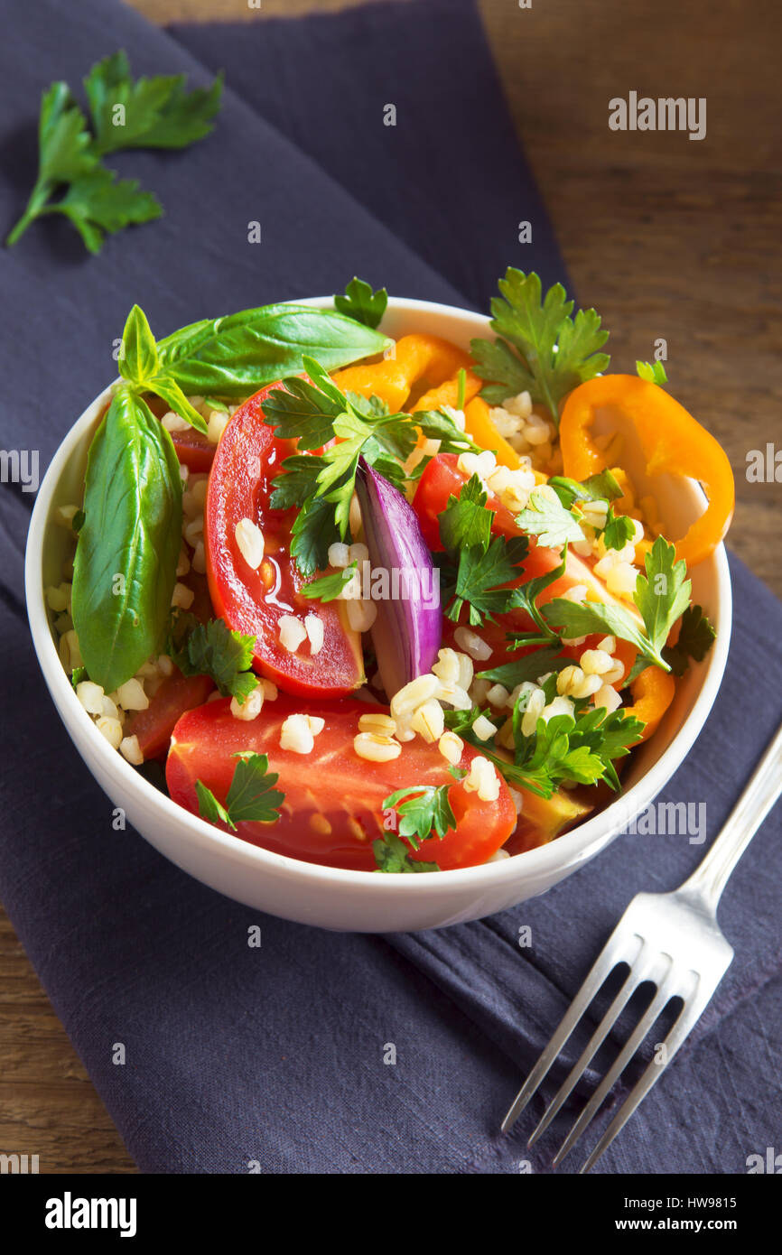 Frische Bio-Tomaten und Bulgur Couscoussalat Taboulé mit Gemüse und grünen - gesunde vegetarische vegane Ernährung traditionellen Salat auf rustikal aus Holz Stockfoto