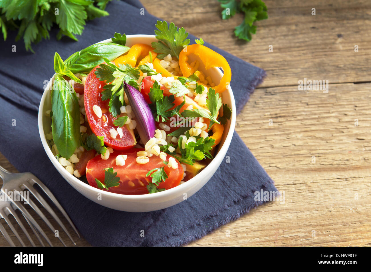 Frische Bio-Tomaten und Bulgur Couscoussalat Taboulé mit Gemüse und grünen - gesunde vegetarische vegane Ernährung traditionellen Salat auf rustikal aus Holz Stockfoto