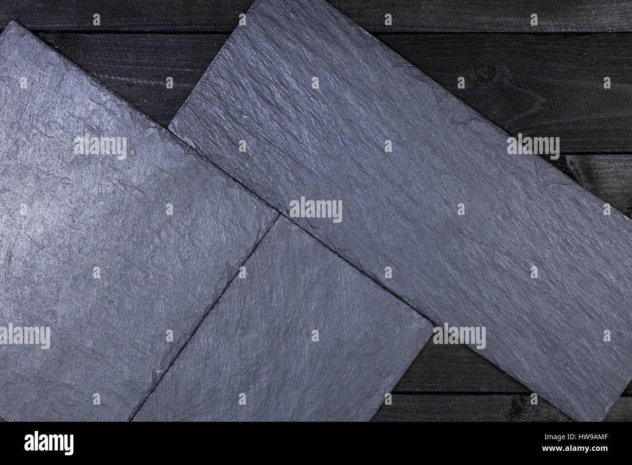 Schiefer Steinplatte auf schwarzer Holztisch, Ansicht von oben mit Textfreiraum Stockfoto