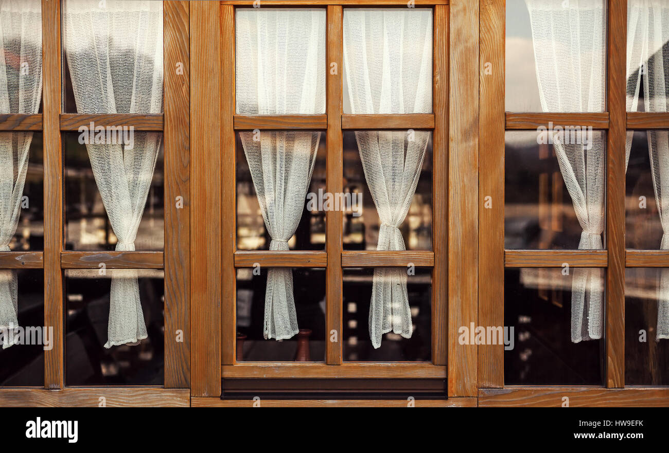 Dekorative Holzfenster mit alten altmodische weiße Vorhänge. Stockfoto