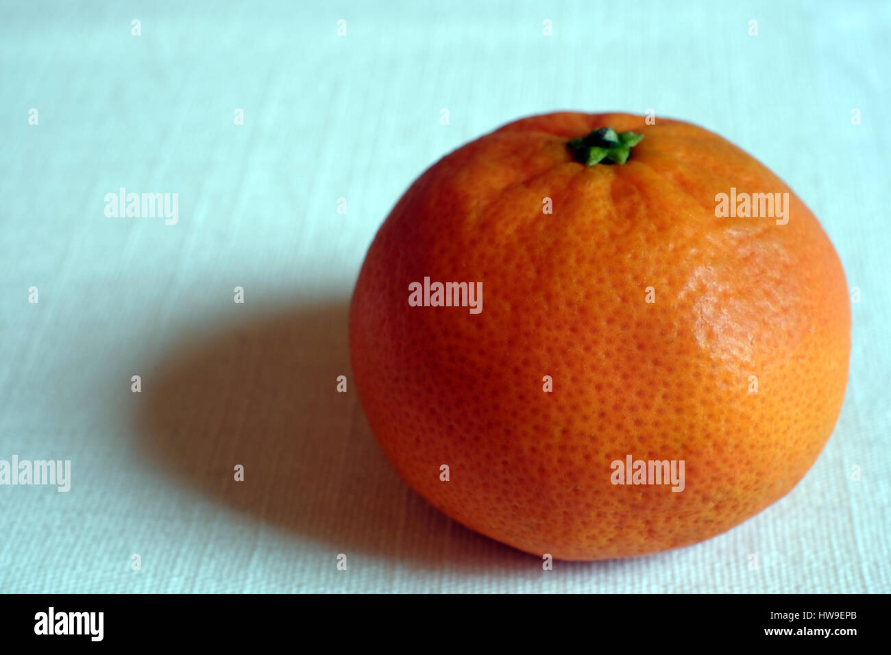 Einer einzigen Mandarine auf einer weißen Tischdecke Stockfoto