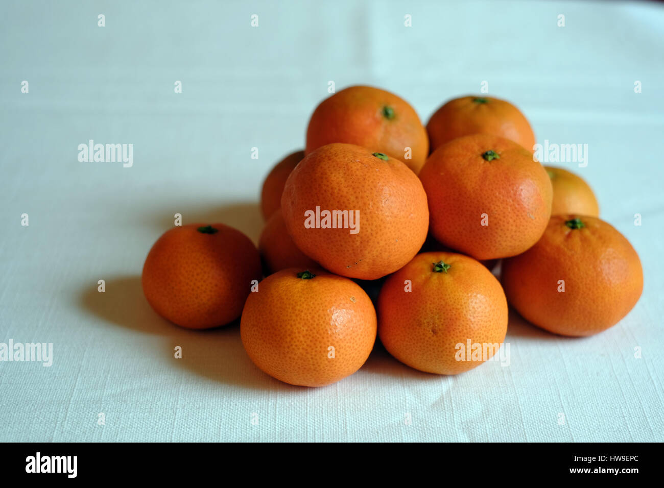 eine Gruppe von Orangen auf einer weißen Tischdecke Stockfoto