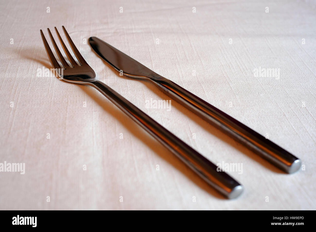 Messer und Gabel auf einer weißen Tischdecke Stockfoto