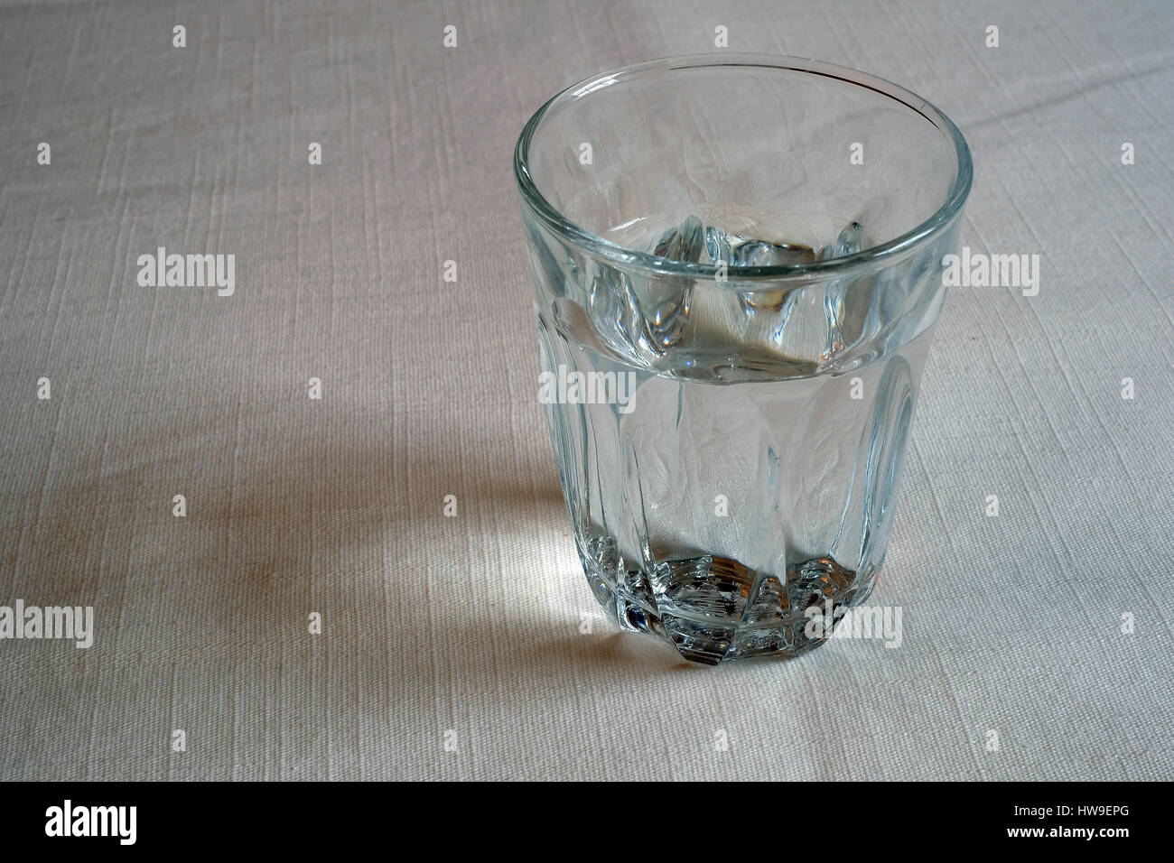 Glas Wasser auf eine weiße Tischdecke Stockfoto