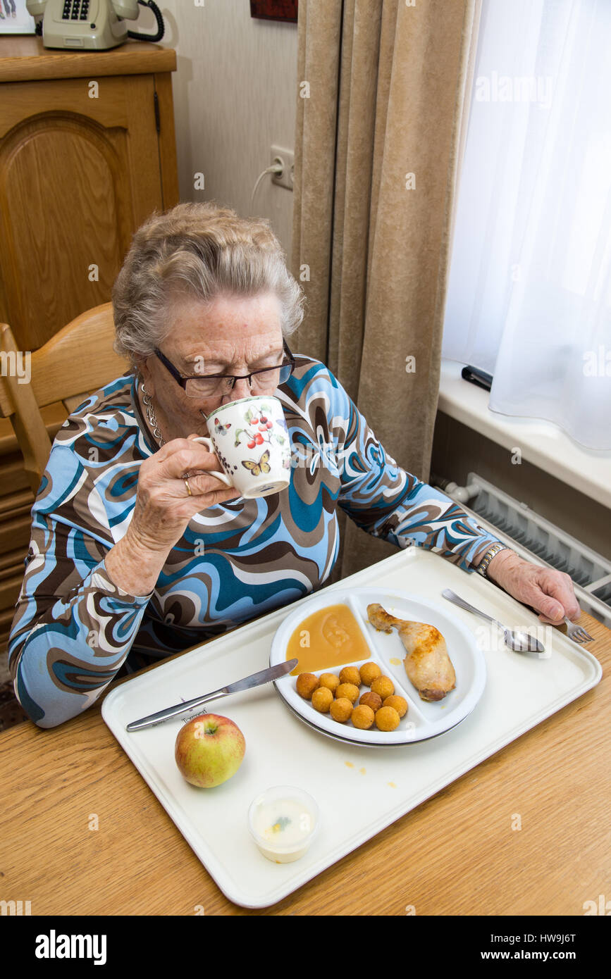 alte Frau Essen am Tisch im Haus der älteren Menschen Stockfoto