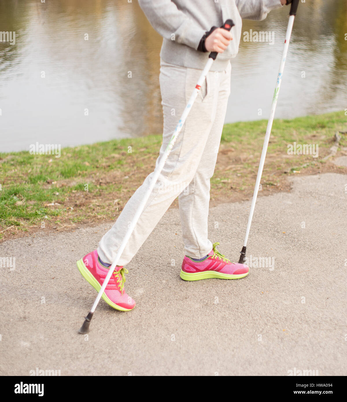 Eine nicht erkennbare Frau mit die Skistöcke im Park neben dem Teich. Stockfoto