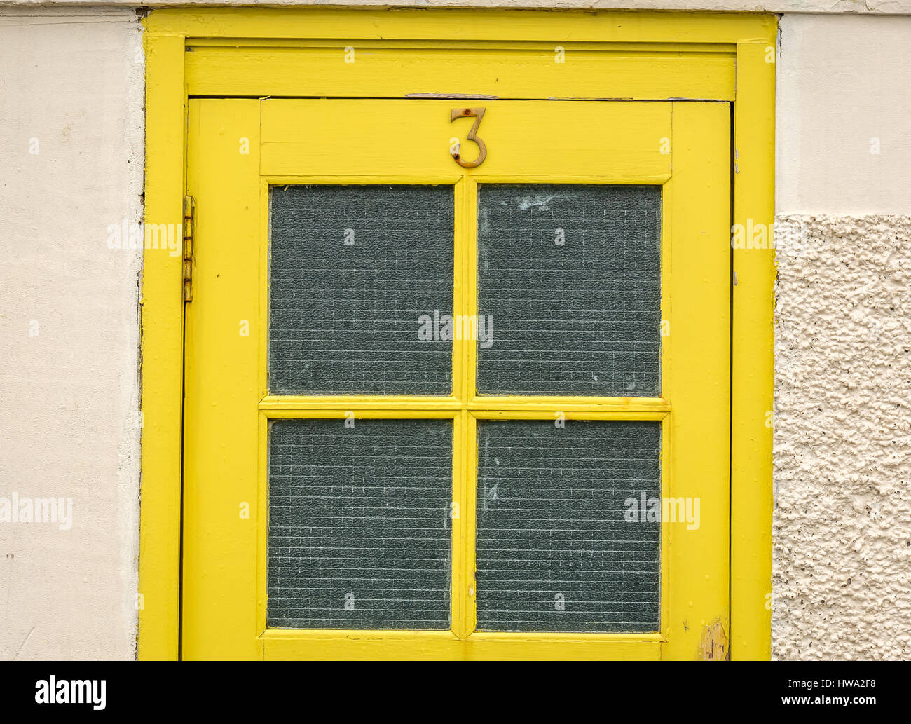 Nahaufnahme eines alten Gelb lackiert Tür mit einer Nummer drei und Fensterscheiben in einer Stadt am Meer, North Berwick, East Lothian, Schottland, Großbritannien Stockfoto