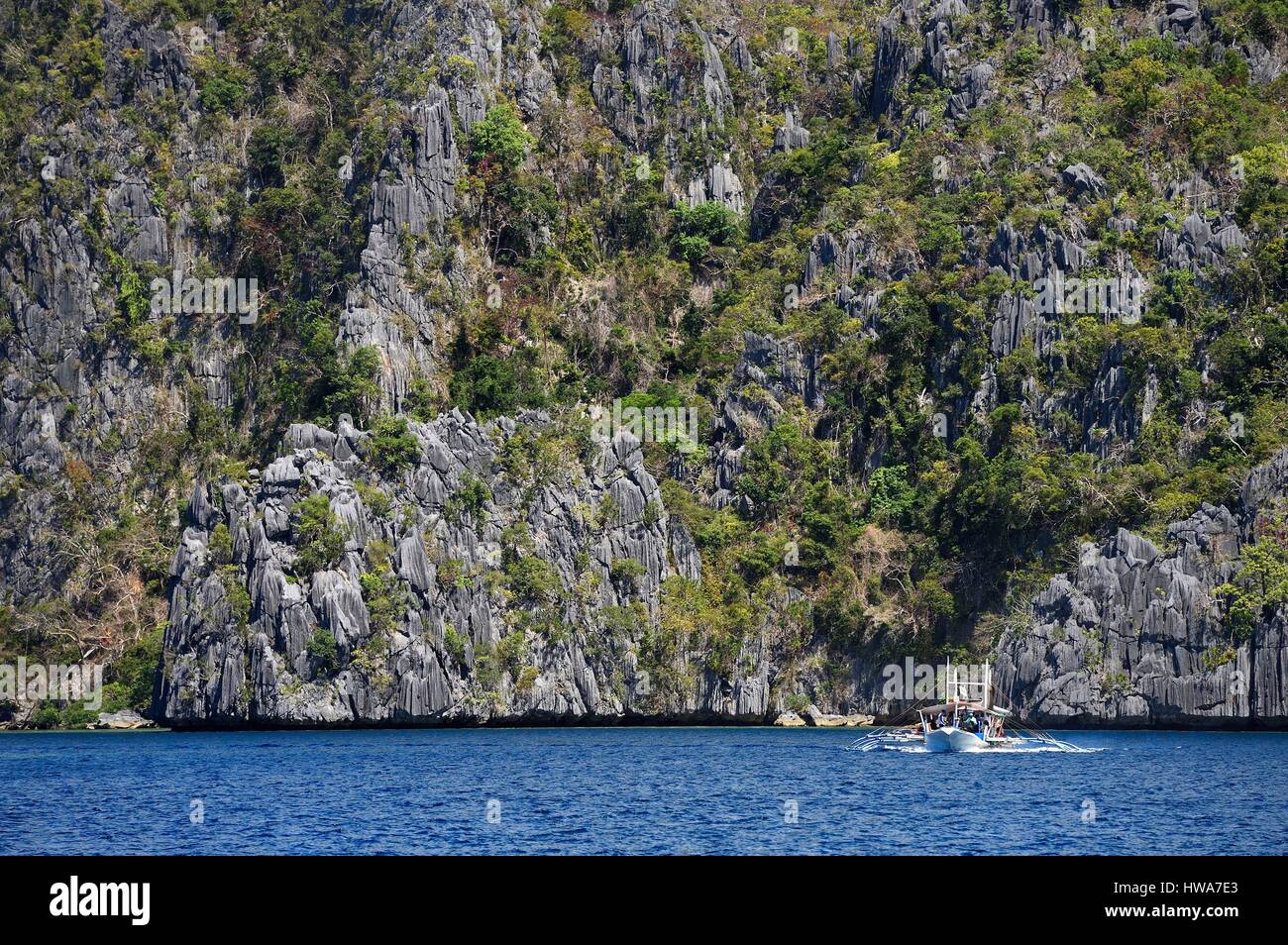 Philippinen, Calamian Inseln im nördlichen Palawan, Coron Island biotische Naturraum, Ausleger-Kanu unter riesigen Mauern von Kalksteinfelsen Stockfoto