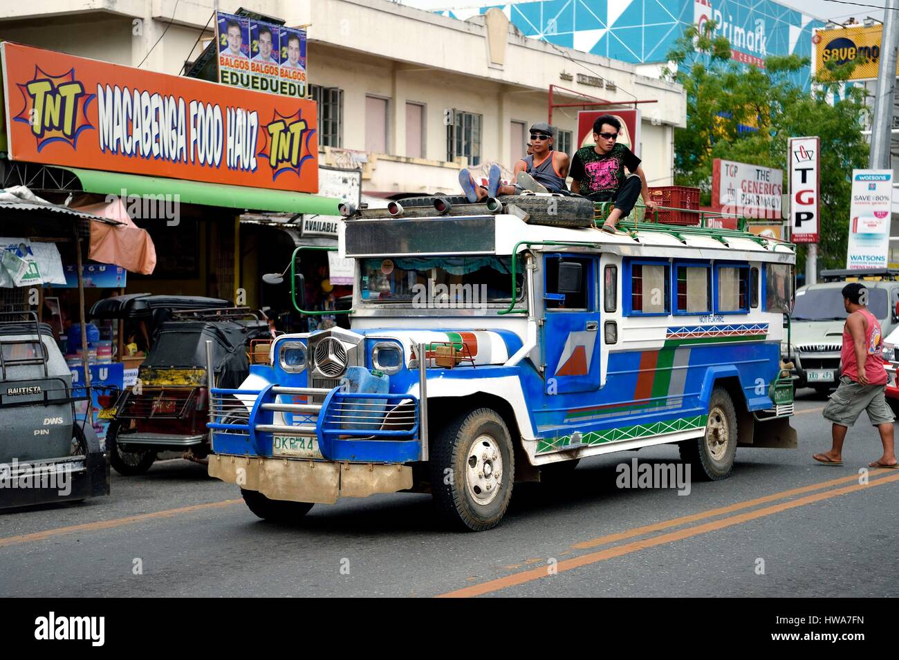 Philippinen, Provinz von Nueva Ecija, Bambang, Jeepney (längliche Jeep, Passagiere zu befördern) mit Passagieren auf Dach in Hauptstraße Stockfoto