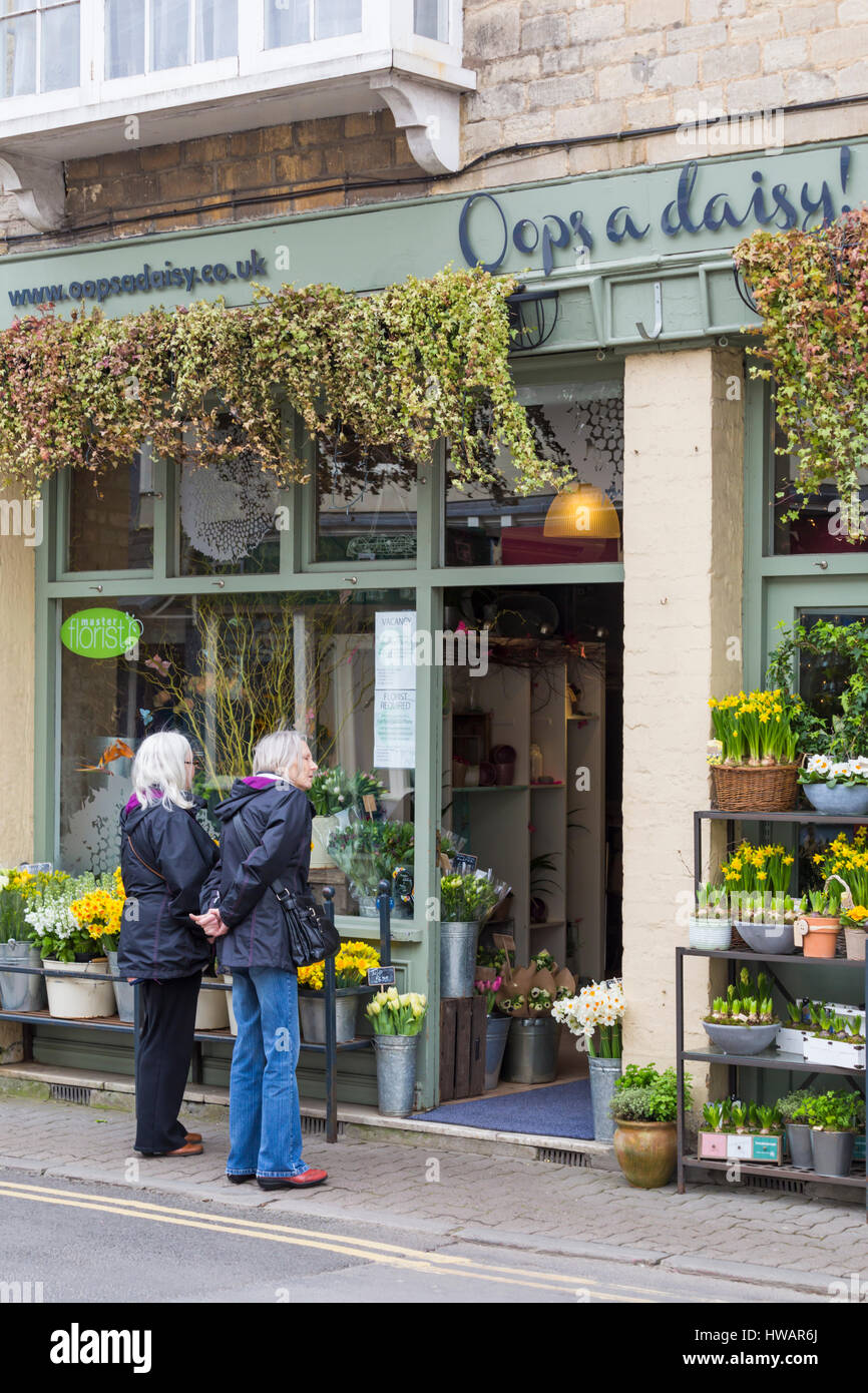 Hoppla ein Daisy-Blumenladen in Cirencester voller Frühlingsblumen, ideal für Muttertag, als paar Frauen suchen im Fenster in Cirencester im März Stockfoto