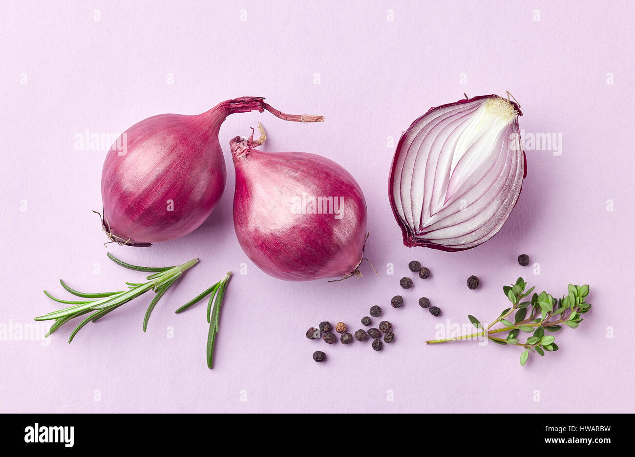 roten Zwiebeln und Gewürze auf lila Hintergrund, Ansicht von oben Stockfoto