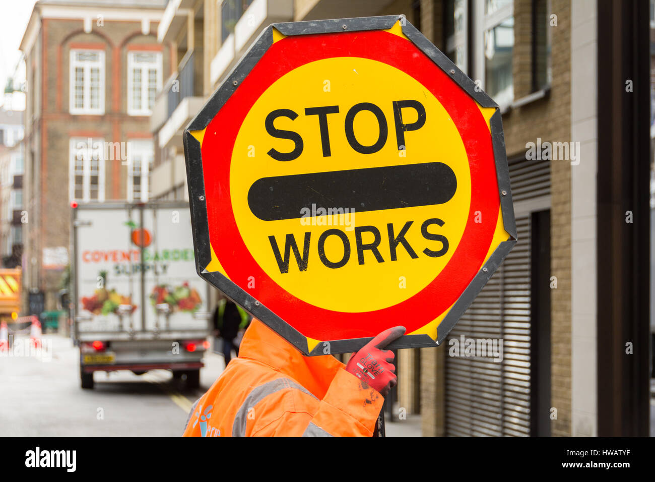 Ein Arbeiter hält ein Schild mit "Stop Works" in Soho, London, UK Stockfoto