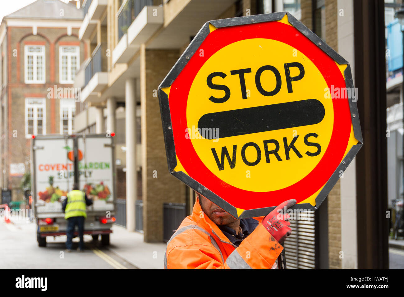 Ein Arbeiter hält ein Schild mit "Stop Works" in Soho, London, UK Stockfoto