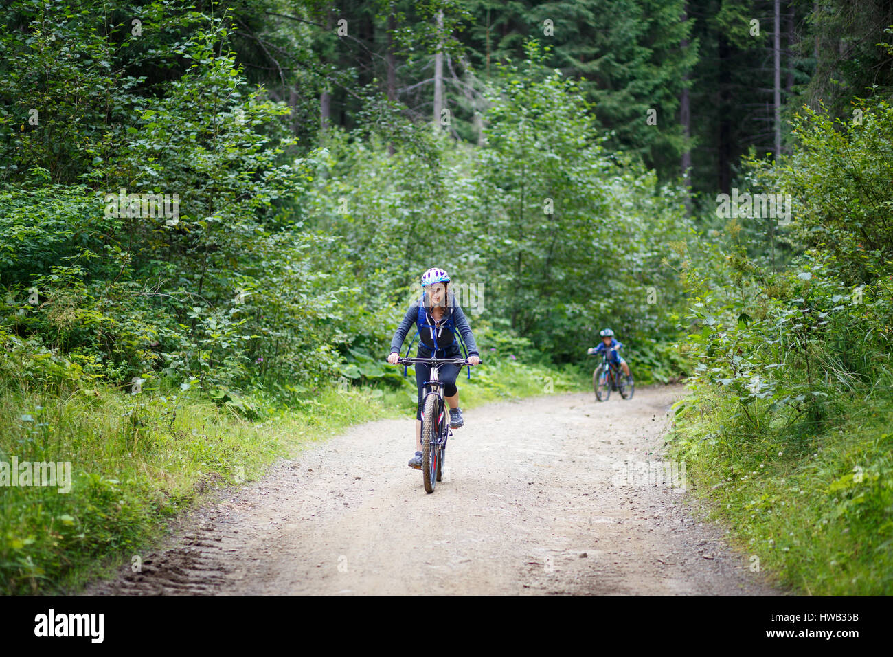 Junge lächelnde Frau junge Frau Reiten Fahrrad im Bergwald an Sommertag Stockfoto