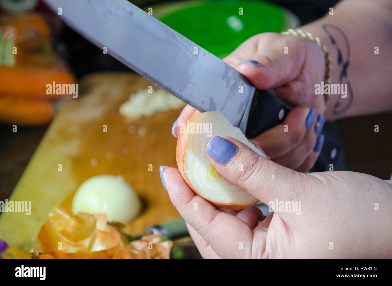 Ein Blick auf eine Frau mit einem großen Messer zu schälen und Zwiebel im Rahmen der Vorbereitung einer Mahlzeit die Hände. Stockfoto