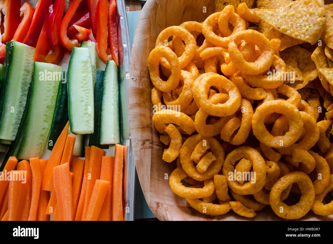 Gesunde und ungesunde Snack Ernährungsgewohnheiten mit Chips und rohe Gemüsestangen nebeneinander von oben gesehen. Stockfoto