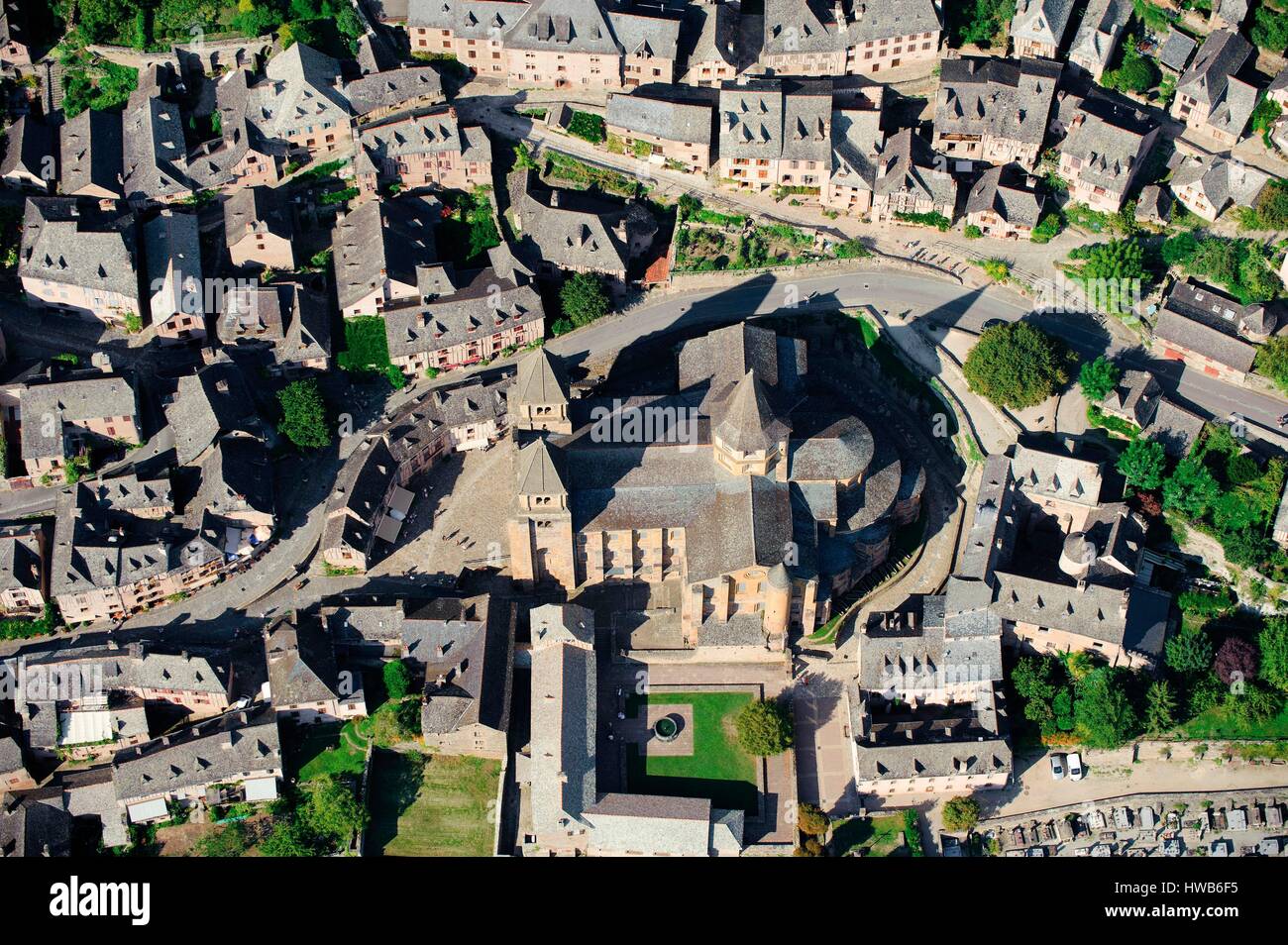 Frankreich, Aveyron, Conques, Sainte Foy ist eine Basilika in lateinischen Kreuzes, mit einem ambulanten, Sicherheiten, Galerien und strahlende Kapellen, das Gebäude ist jetzt durch die Glasfenster, gestaltet von Pierre Soulages (1994) (Luftbild) leuchtet Stockfoto