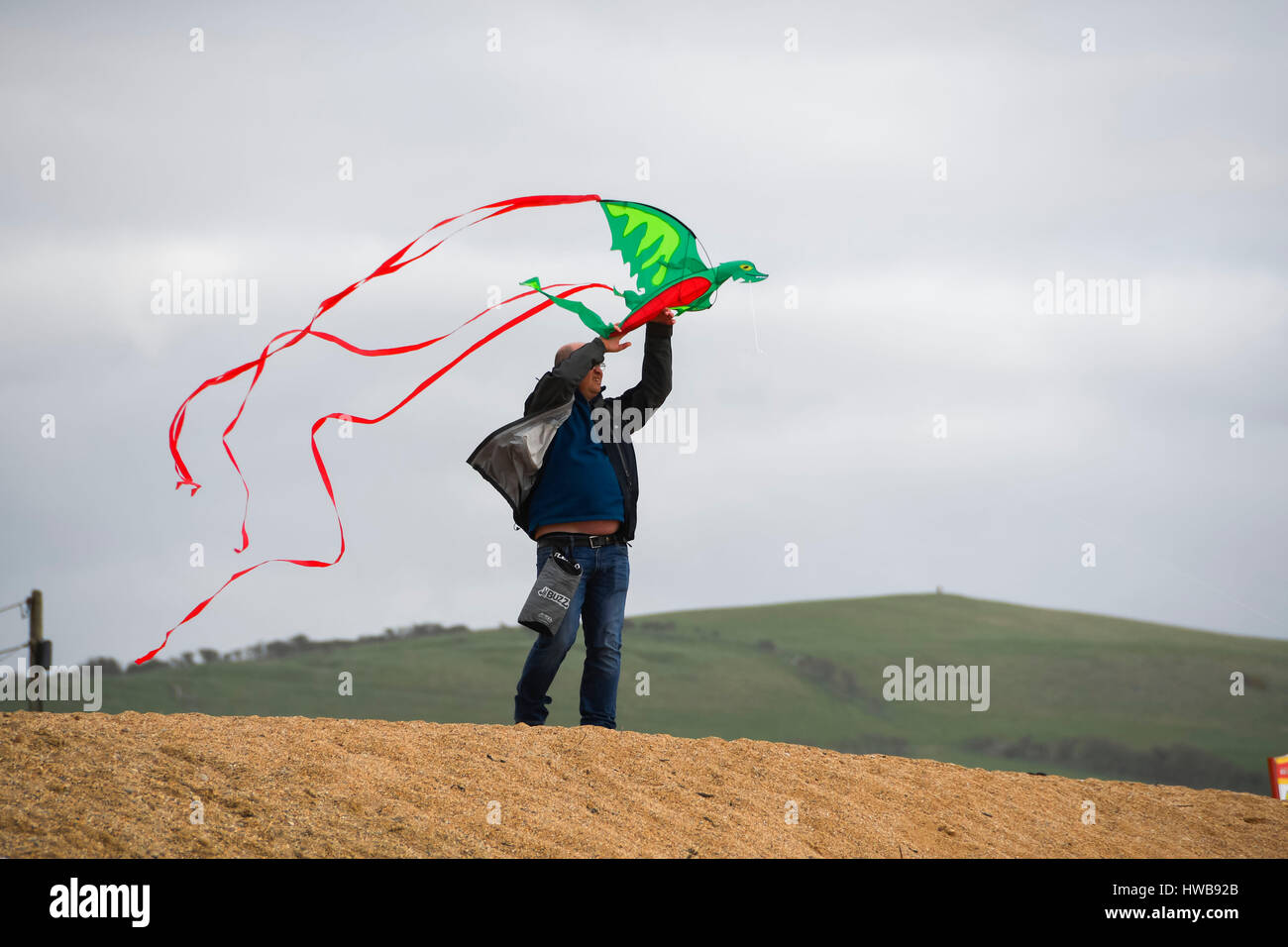 West Bay, Dorset, UK.  19. März 2017.  Großbritannien Wetter.   Ein Mann Lauching ein Kite am East Beach an einem bewölkten windigen Tag in West Bay in Dorset.  Bildnachweis: Graham Hunt/Alamy Live-Nachrichten Stockfoto