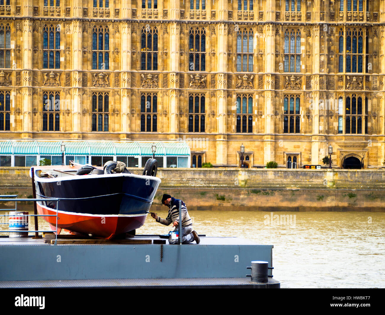 Mann, die Malerei ein Boot vor Westminster - London, England Stockfoto
