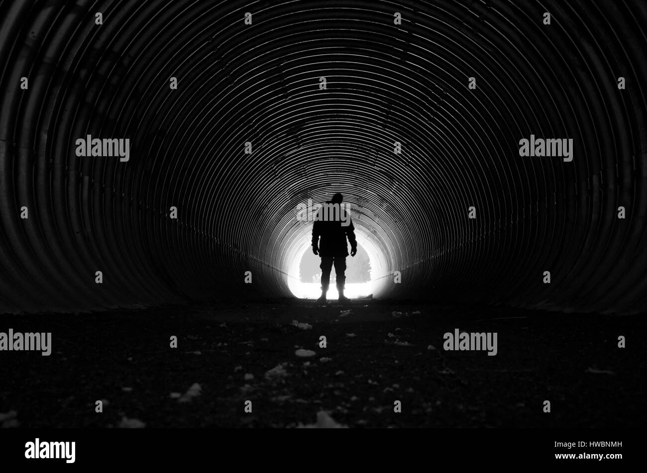 Menschen im dunklen Tunnel mit Licht am anderen Ende stehen. Schön, mystisch und poetischen schwarz-weiß-Foto. Ruhige und friedliche Stimmung. Stockfoto