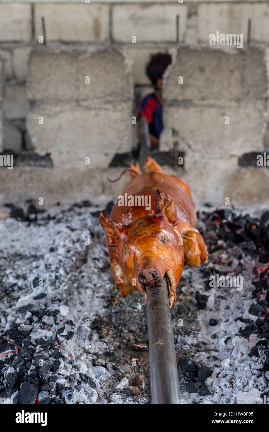 Ein ganzes Schwein gekocht wird und die Hand umgedreht Holzkohle Glut, die philippinische Gericht Lechon mit Vordergrund Fokus Schärfentiefe zu erstellen. Stockfoto