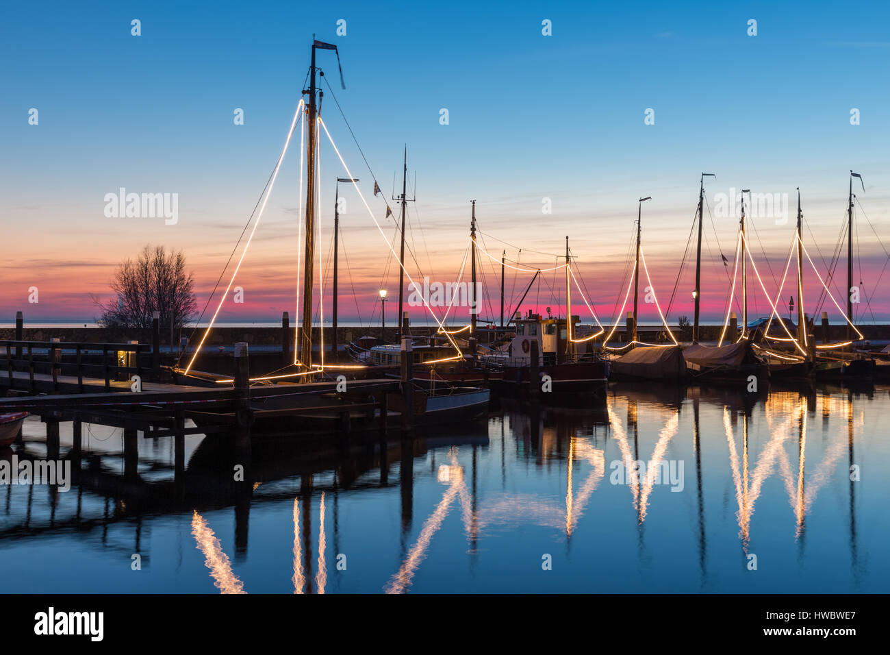 Beleuchtete traditionelle hölzerne Fischerboote in der Nacht im niederländischen Hafen von Urk Stockfoto