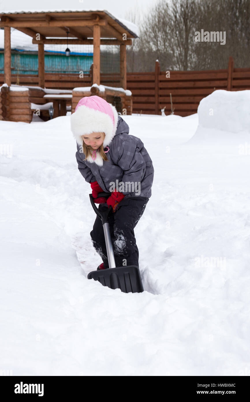 Mädchen nimmt den Schnee abseits der Pfade mit einer Schaufel Stockfoto