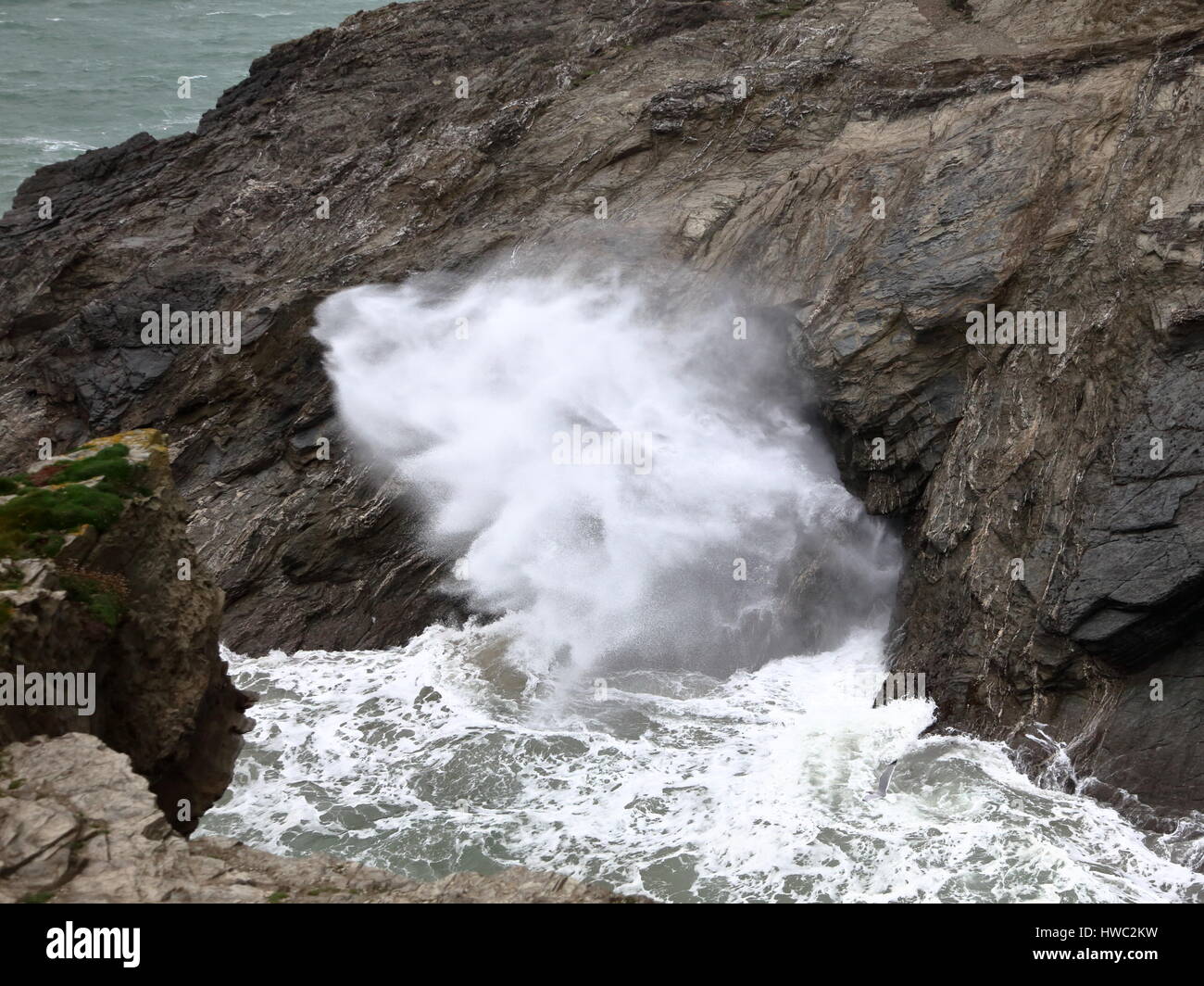 Massiver Anstieg der Sturmwellen betreten seewärtigen Höhle an Spitze der Porth Insel gezwungen spektakuläre Wasser-Auswurf durch Schlag Loch auf Flanke, Cornwall UK Stockfoto