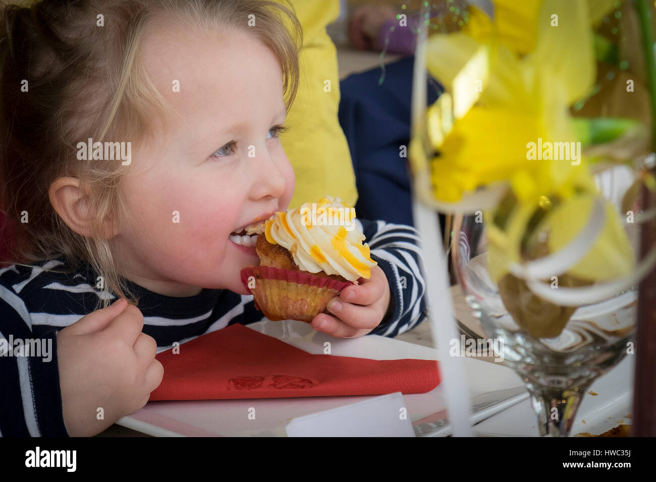 Hübsche blonde Kind Mädchen junge genießen essen Kuchen Cupcake Stockfoto