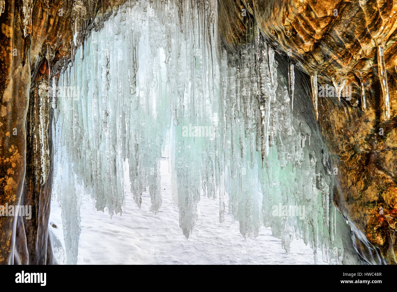Lange Eiszapfen am Bogen der kleinen Grotte in küstennahen Felsen. Blick aus dem Inneren. Der Baikalsee. Olchon Stockfoto