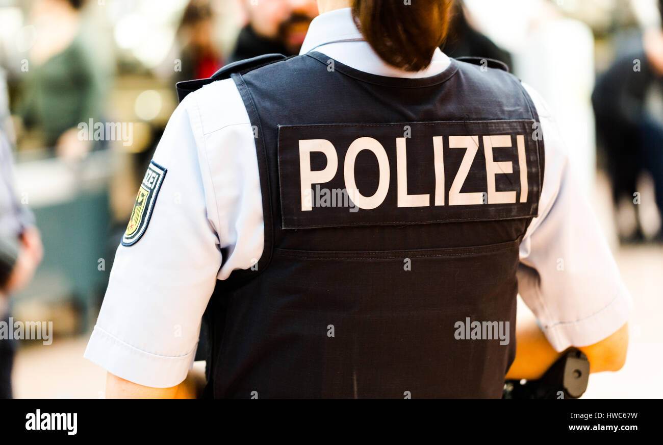 Deutscher Polizist Frau auf dem Flughafen Hamburg beobachtet Passagiere. Hinteren Schuss konzentrieren sich auf kugelsichere Weste mit Polizei Badget. Flughafen Hamburg, 13 Stockfoto