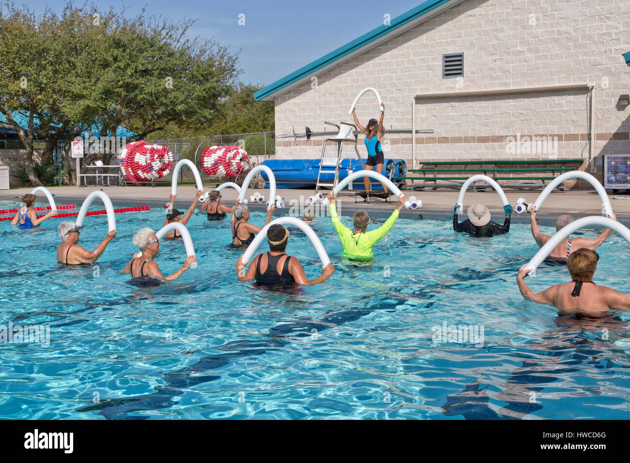 Gruppe von Frauen, Wasser-Aerobic-Kurs teilnehmen, Ausbilder demonstriert, mit Styropor "Wasser Nudel", Outdoor-beheizter Pool, Rockport, Texas. Stockfoto